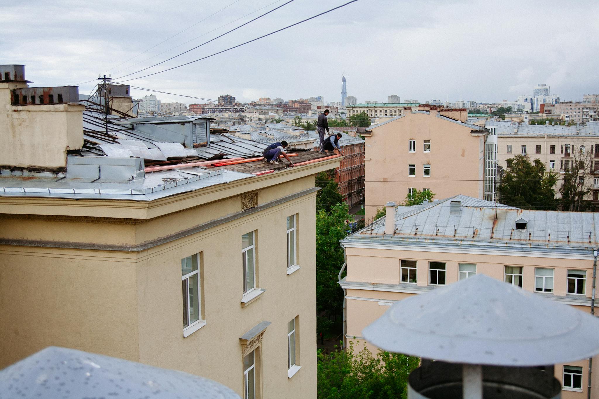 Construction workers repairing a rooftop in a vibrant cityscape.