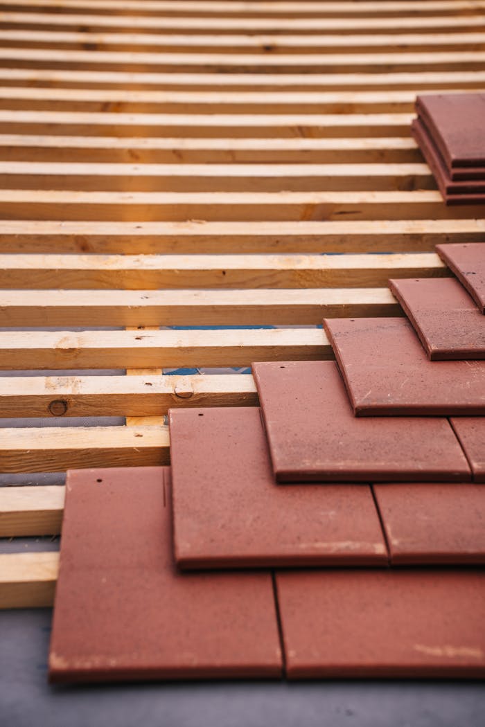 Red roofing tiles and wooden framework in progress on a building roof.